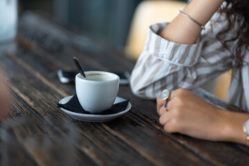 woman with rings and watch having a cup of coffee at wooden table