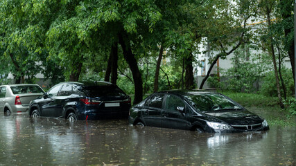 Flooded cars on the street of the city. Street after heavy rain. Water could enter the engine, transmission parts or other places. Disaster Motor Vehicle Insurance Claim Themed. Severe weather concept - obrazy, fototapety, plakaty