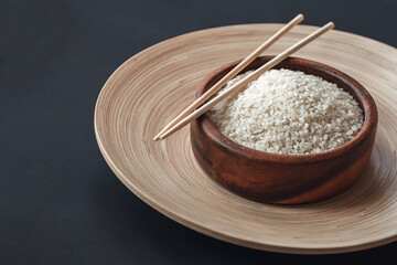 White rice in wooden bowl with wooden chopsticks