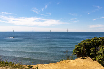 A wind turbine farm out on the horizon from the shore