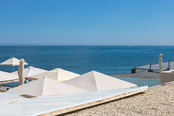 Beach holidays by the sea. White linen umbrellas from the sun on the background of the sea.