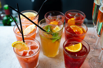 Set of cocktails and champagne in a glass on the bar table top made for party guests. Dark background of loft wall.