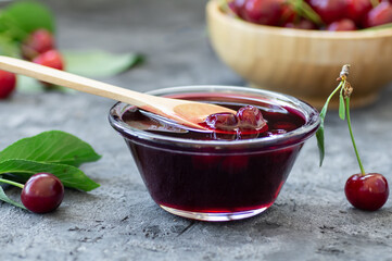 Sour cherry jam in spoon and glass bowl with fresh raw sour cherries