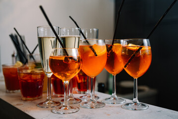 Set of cocktails and champagne in a glass on the bar table top made for party guests. Dark background of loft wall.