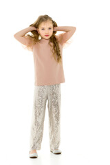 A little girl fixes her hair. The concept of beauty and fashion