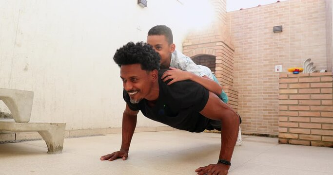 African father doing push up with son on back