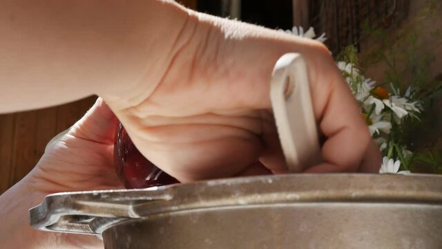 time-lapse photography fresh strawberry jam by the hands of a Caucasian woman is placed in a transparent jar from a metal pan. Close-up. View from below