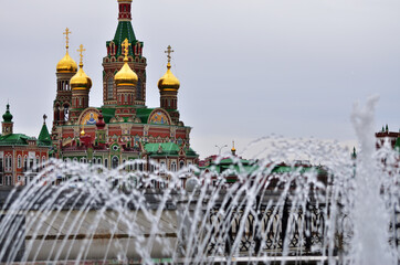 The Cathedral of the Epiphany in the foreground of the fountain jet is cloudy weather. Russia Yoshkar-Ola 01.05.2021. High quality photo
