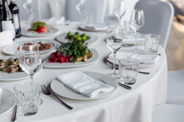 Table setting for a banquet or celebration. Empty wine glasses for spirits, champagne and juice. Set the table. Cloth napkins on a platter. Banqueting hall. Cold appetizers and salads.