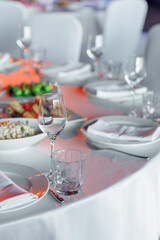 Table setting for a banquet or celebration. Empty wine glasses for spirits, champagne and juice. Set the table. Cloth napkins on a platter. Banqueting hall. Cold appetizers and salads.
