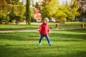 Adorable toddler girl playing in autumn park