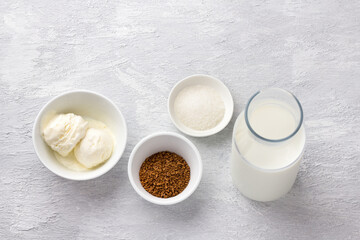 Ingredients for dalgona coffee. Instant coffee, milk, ice cream and sugar. Light gray textured background, top view