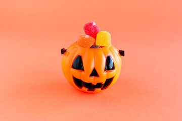 Happy Halloween decoration. Pumpkin and gummy candies on orange background.
