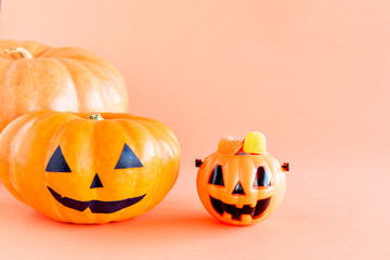Happy Halloween decoration. Pumpkin and gummy candies on orange background.
