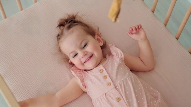 Childcare at Home, Child Protection, New Life, Leisure with Baby. Happy baby lies in a crib