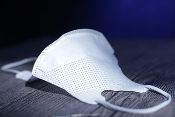 Protective face mask lying on wooden table, covid coronavirus pandemic prevention new normal