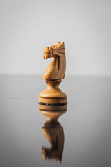 the knight chess piece on white background with reflection in table.