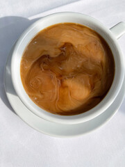 Looking straight down on large coffee with unstirred creamer
