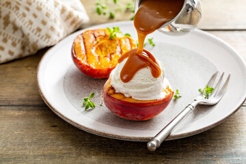 Grilled peaches with ice cream and caramel sauce, summer dessert