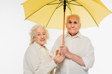 happy elderly couple holding yellow umbrella isolated on white - Powered by Adobe