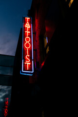 Obraz premium Red neon sign of the word Tattooist on a black background.