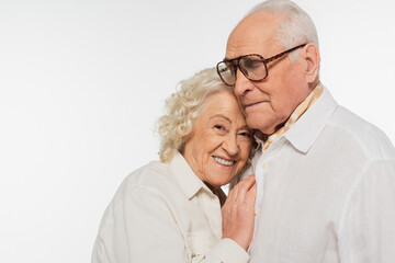 elderly woman gently hugging senior man with hand on breast isolated on white