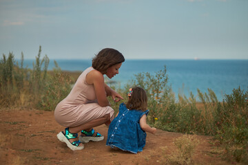 Woman and child look at each other against the background of the sea