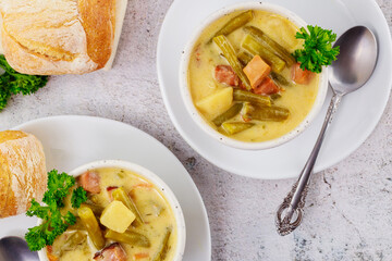 Top view of healthy vegetable soup with bread in white plate.
