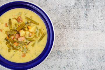 Homemade vegetable soup with cut beans in blue plate.