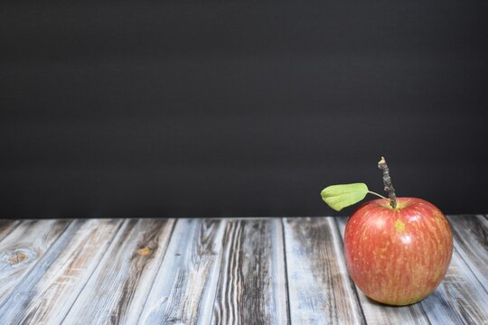 Red apple with a black background and wood table