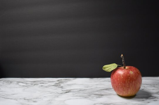 Red apple with a black background and marble table