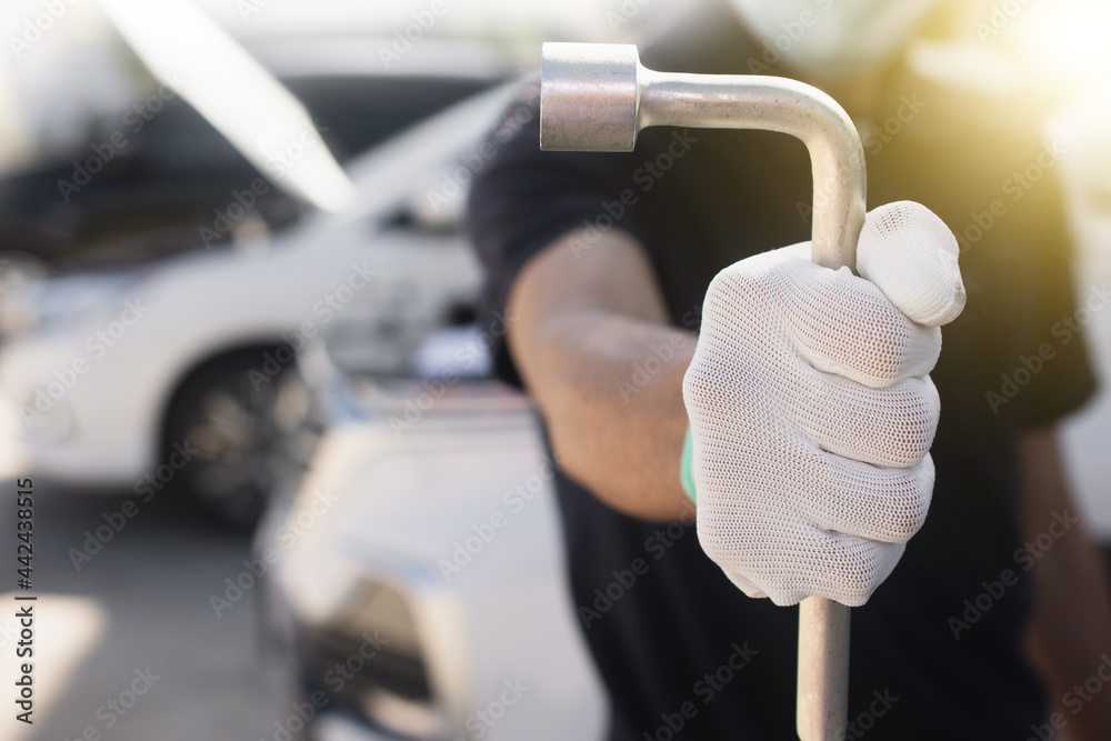 Wall mural close up repairman holding socket wrench in car garage