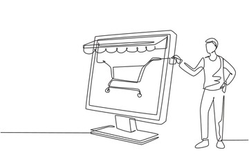 Single one line drawing young man inserting credit card into canopy monitor screen with shopping cart. E-shop, digital payment concept. Modern continuous line draw design graphic vector illustration