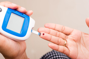 woman measuring glucose test level check with blood on finger by glucometer