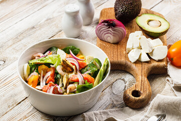 Delicious and healthy Mediterranean summer salad. Mussels, shrimp, salmon, tomatoes, ice salad, avocado, red onion, spices, and olive oil. Gourmet still life of seafood on a rustic background.