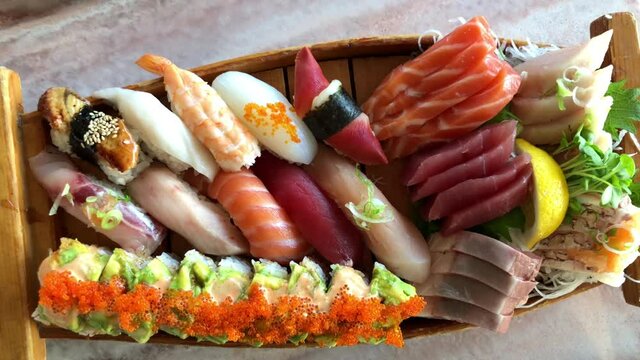 4K HD video zooming in on a sushi boat with a variety of freshly prepared sushi in a wood boat bowl
