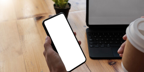 Mockup image blank white screen cell phone.women hand holding texting using mobile on desk at home office.