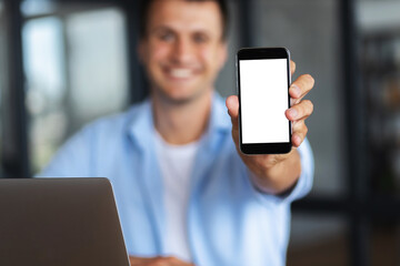 Mobile phone with blank screen in the hands of a young caucasian man, shows a smartphone with blank screen