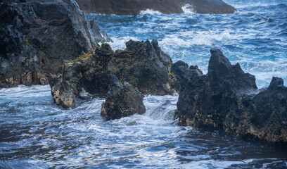 Sea background. Ocean wave crashing on rock coast with spray and foam before storm.