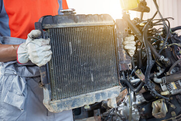 Auto mechanics holding broken car radiator in auto service, technician doing the checklist for...