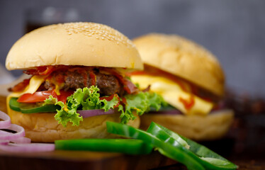 Ready to eat homemade hamburger with glass of drink in background. Taken with dark style light