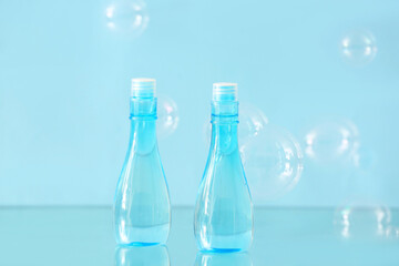 Bottles of cosmetic products with bubbles on color background