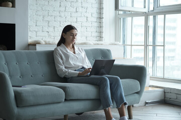 Fototapeta premium Thoughtful female blogger using laptop for writing posts in social network. 