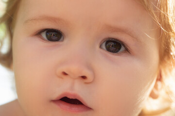 Close up portrait of a small blond baby boy, cropped face. Funny kids face.
