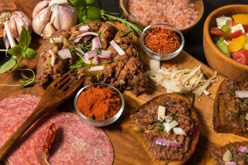 Traditional homemade French steak tartare of raw beef. Steak tartar with chopped onion and herbs on wooden board.