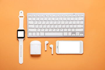 Modern earphones, mobile phone, smart watch and computer keyboard on color background