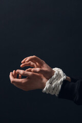 Female hostage with tied hands on dark background, closeup