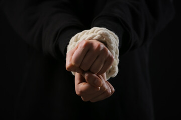 Female hostage with tied hands on dark background, closeup