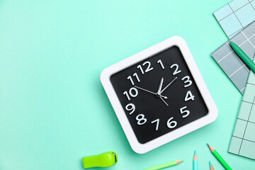 Stylish clock with stationery on color background