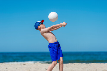 Young boy playing volleyball on beach. Summer sport concept.